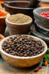 Indian spices collection, dried black peppercorns and another spices in clay bowls