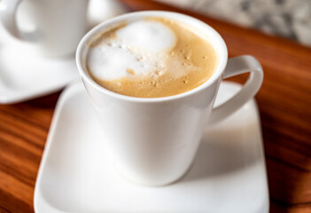 White cup of coffee latte served in outdoor cafe in France