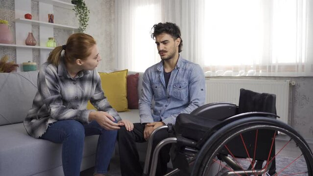Disabled man in wheelchair and his girlfriend talking.
The girl who gives moral and support to her sad disabled friend is doing her best.
