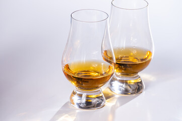 Tulip-shaped tasting glasses with dram of Scotch single malt or blended whisky on white background