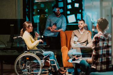 Businesswoman in wheelchair having business meeting with team at modern office. A group of young freelancers agree on new online business projects