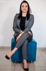 A mulher empreendedora em uma sessão de fotos corporativa em pose sentada no banco e sorridente...