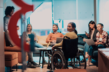 Businesswoman in wheelchair having business meeting with team at modern office. A group of young freelancers agree on new online business projects