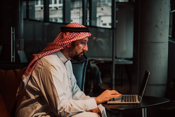 Fototapeta na wymiar An elderly Arab man sitting in the office and analyzes data on his laptop