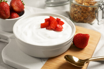 Delicious yogurt served with strawberries on grey marble table