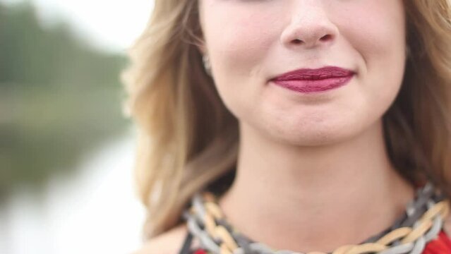 Close up of lips of beautiful young woman. The woman is slowly smiling.