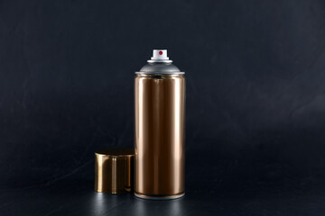 Golden can of spray paint on black background. Space for text
