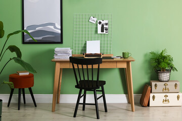 Typewriter, stack of papers and mood board on wooden table near pale green wall. Writer's workplace