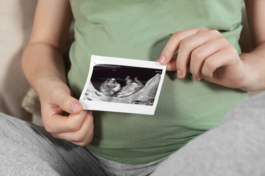 Pregnant woman with ultrasound picture of baby, closeup