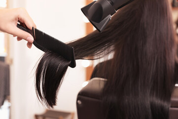 Fototapeta premium Hairdresser drying woman's hair in beauty salon, closeup