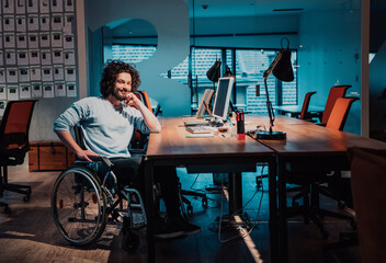 Businessman with a disability in wheelchair working overtime alone at his desk in an office late at night