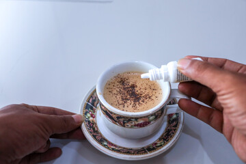 hand adding liquid sugar or molasses to a cup of coffee