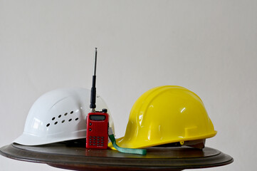 Closeup of White and Yellow Helmet and Radio Communication placed on wooden table in construction...