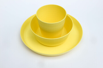 Yellow plastic dinnerware, bowl, plate and cup isolated on white background