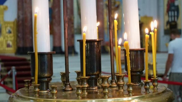 Burning votive candles in candlesticks stand on a small table in front of icons in the church. People pray for health or for the repose, or as sign of their faith and hope in help of God.