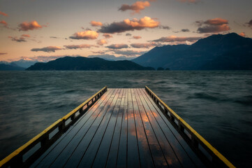 Sunrise Look at a Wooden Dock Extending Out Over a Lake Towards Islands and Forests. Harrison Lake...