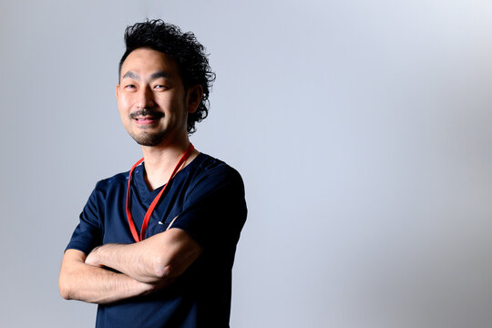 腕を組むスクラブを着た男性ドクターのイメージ