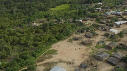Aerial shot of children playing soccer in a forest village, in Ivory Coast