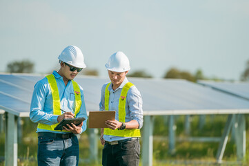 Fototapeta na wymiar Asian young inspector engineer man and friend checking solar panel in solar farm