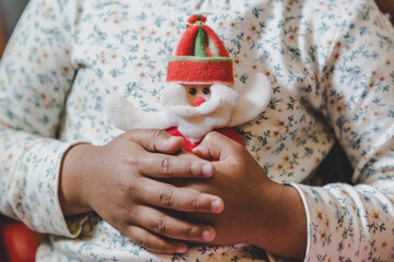 niña feliz y sonriente sosteniendo en sus manos objetos decorativos navideños, bolas o esferas navideñas  y letras de feliz navidad en ingles, concepto navidad, amor, paz y compartir. 