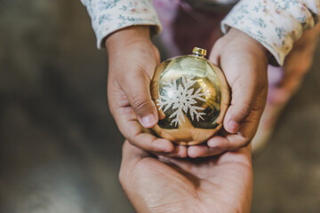 niña feliz y sonriente sosteniendo en sus manos objetos decorativos navideños, bolas o esferas...