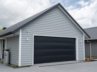 Double gray garage with black tilt-up retractable raised panel metal door and gable metal roof