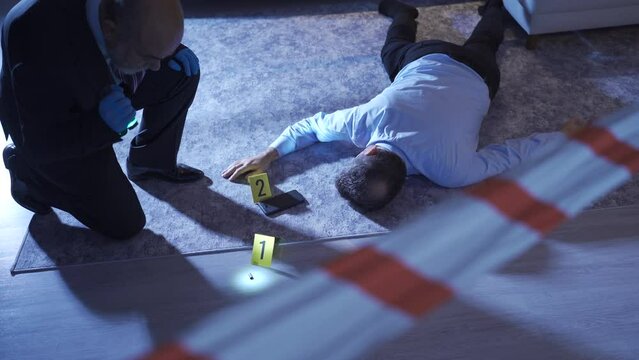 Detective looking at the body of the murdered victim at home.
Detective examining corpse and evidence at crime scene.
