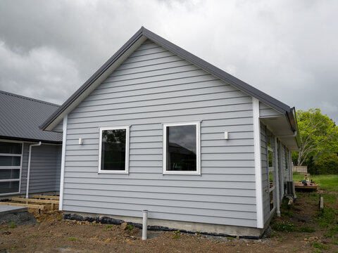 Brand new gray weatherboard house with gable roof and two windows.