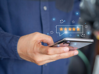 Customers send rating of their satisfaction with the product or service with happiness on a smartphone showing five stars and a smiley face icon. Customer review satisfaction feedback survey concept.