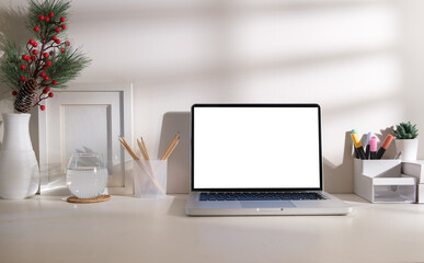 Fototapeta premium Front view of laptop with blank screen, picture frame and stationery on white table.