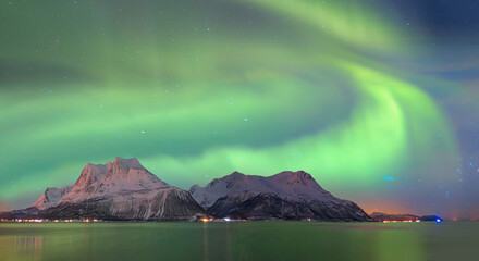 Northern lights (Aurora borealis) in the sky over Tromso, Norway - Aurora reflection on the sea on the background Norwegian fjord - Winter season.