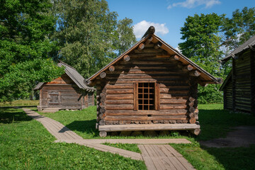 Fototapeta na wymiar View of the log wooden house in the Novgorod Museum of Folk Wooden Architecture of Vitoslavlitsa on a sunny summer day, Veliky Novgorod, Russia