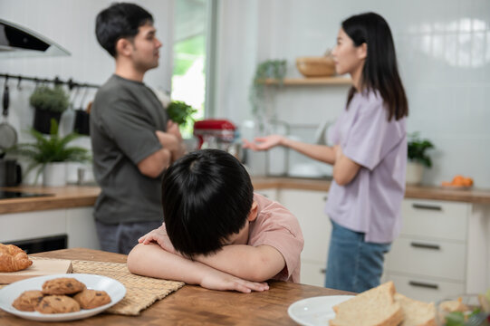 Young little Asian kid feel sad upset, boring while parent fighting arguing or quarrel, sad little boy crying with psychological problem caused by mom and dad family conflicts or violence concept.