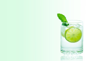 A Glass of gin and tonic cocktail with ice cube, garnished with a lime slice and mint isolated on a white background.