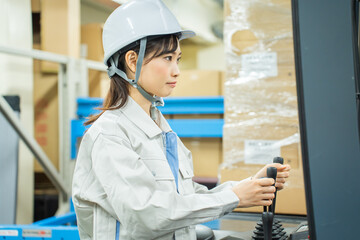 Fototapeta na wymiar フォークリフトで仕事をする日本人女性