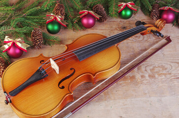 Fototapeta na wymiar Violin with a bow and Christmas decorations on a wooden texture background.