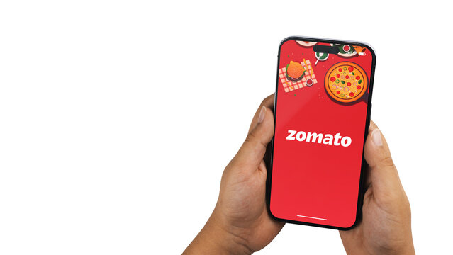Boy holding a smartphone iPhone 14 Pro with Zomato delivery app on the screen. White background. Rio de Janeiro, RJ, Brazil. November 2022
