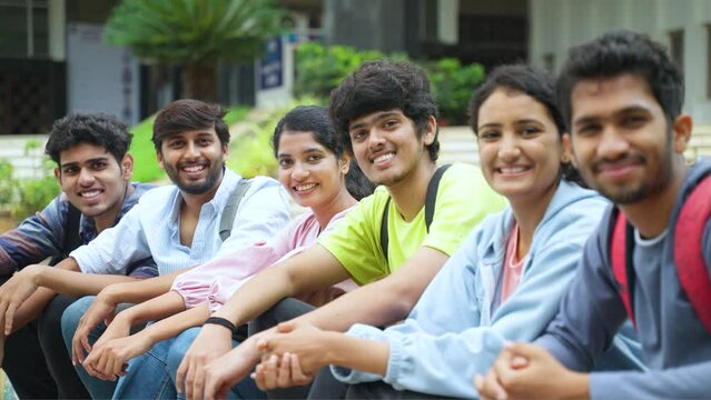 Happy smiling group of college students looking camera while sitting at university campus - concept of education, confident and friendship.
