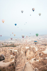 Stunning view some hot air balloons flying over the beautiful Cappadocia landscape during a cloudy day. Goreme, central Antolia, Turkey.