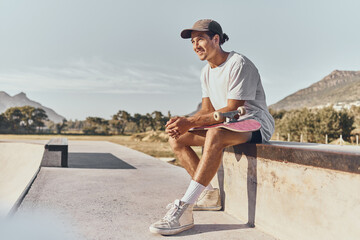 Skateboard, fitness and recreation with a sports man sitting on a wall at a skatepark during the day. Exercise, training and skating with a male athlete or skater having fun outdoor in summer