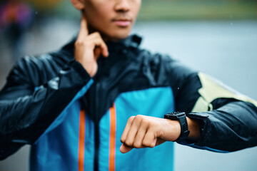 Close up of sportsman using fitness tracker and checking his heart rate outdoors.