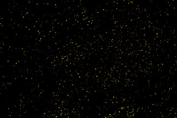 Gold glitter powder sparkling on black background.texture christmas