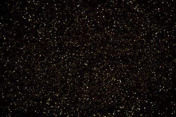 Gold glitter powder sparkling on black background.texture christmas