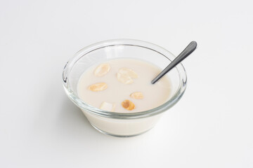 A bowl of plain oat yogurt topped with sliced almonds isolated on a white background. Non-dairy full-fat yogurt alternative.