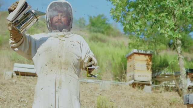 Beekeeper blowing smoke to prevent bees from stinging