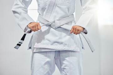karate belt, martial arts and woman ready for fight battle, white dojo training or fitness challenge workout. Warrior motivation, taekwondo and hands of girl learning self defense for safety security © Irshaad M/peopleimages.com