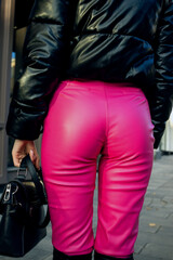 Fototapeta na wymiar Standing on the street with her back a girl in tight pink trousers
