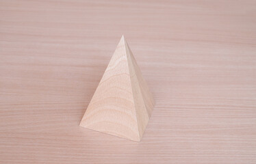 Wooden pyramid geometric model shape on wood table background. Perfect geometry bodies concept