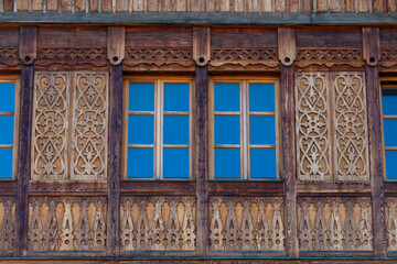 Fototapeta na wymiar Windows on the wooden facade of a rustic house made of wooden beams in a mountains Carpathian village, Western Ukraine, Europe