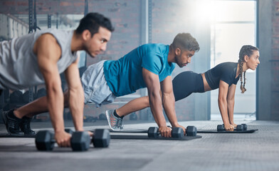 Group, workout and dumbbell push up at gym for muscle, power or strength. Teamwork, sports or energy of people, athletes or bodybuilder friends exercise or training at fitness center for healthcare. - obrazy, fototapety, plakaty